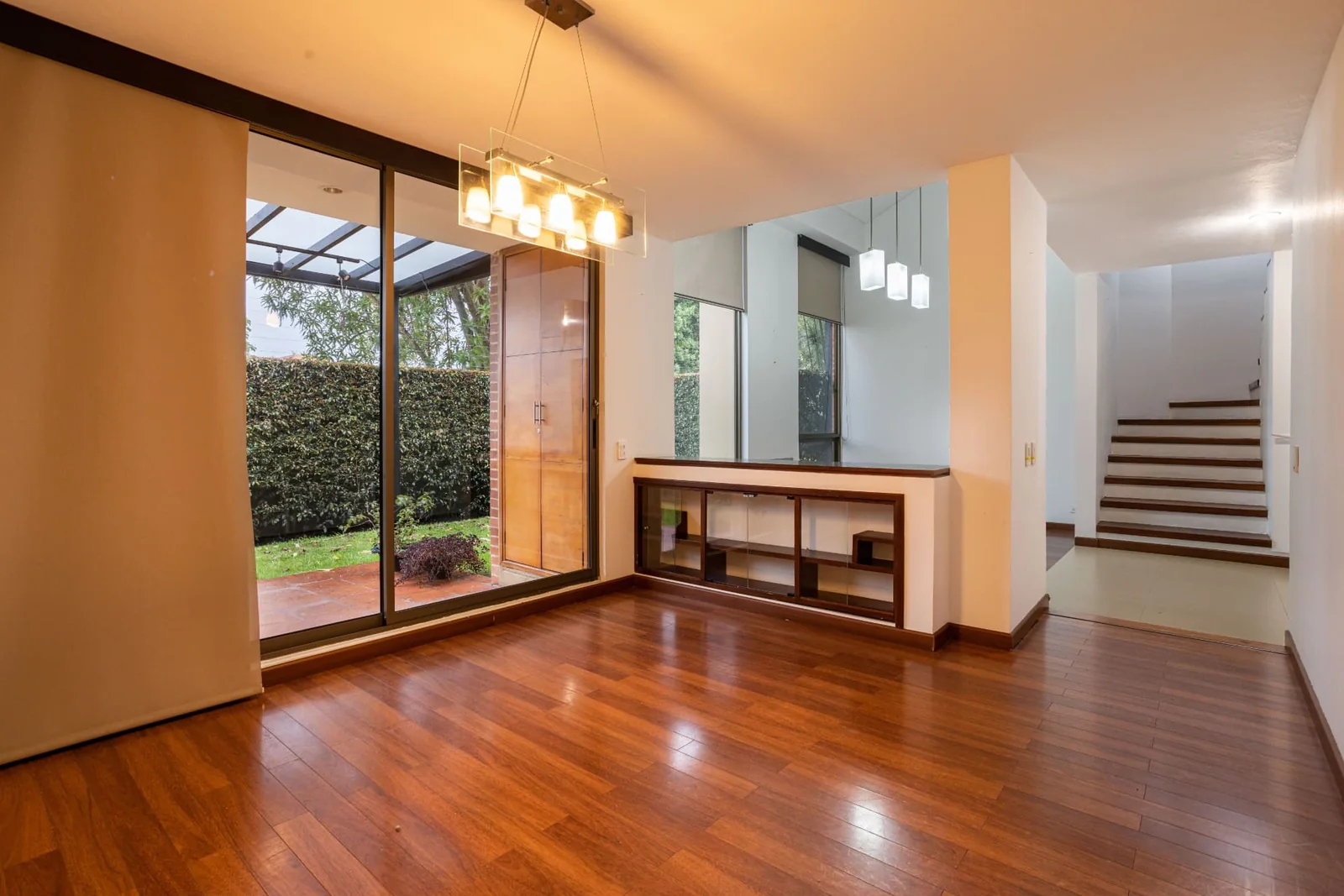 Sala integrada com piso de madeira e acesso ao jardim por porta de vidro
