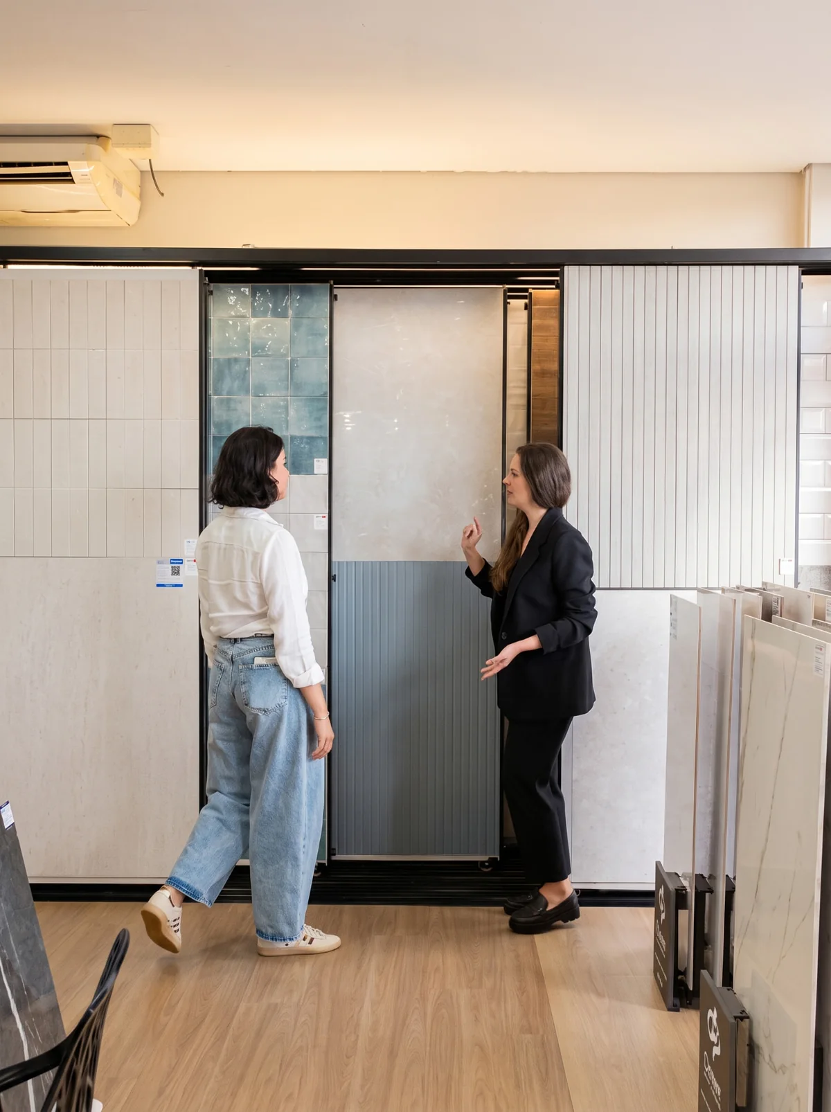 Consultora apresentando painéis de revestimento a uma cliente no showroom da Neo Reveste